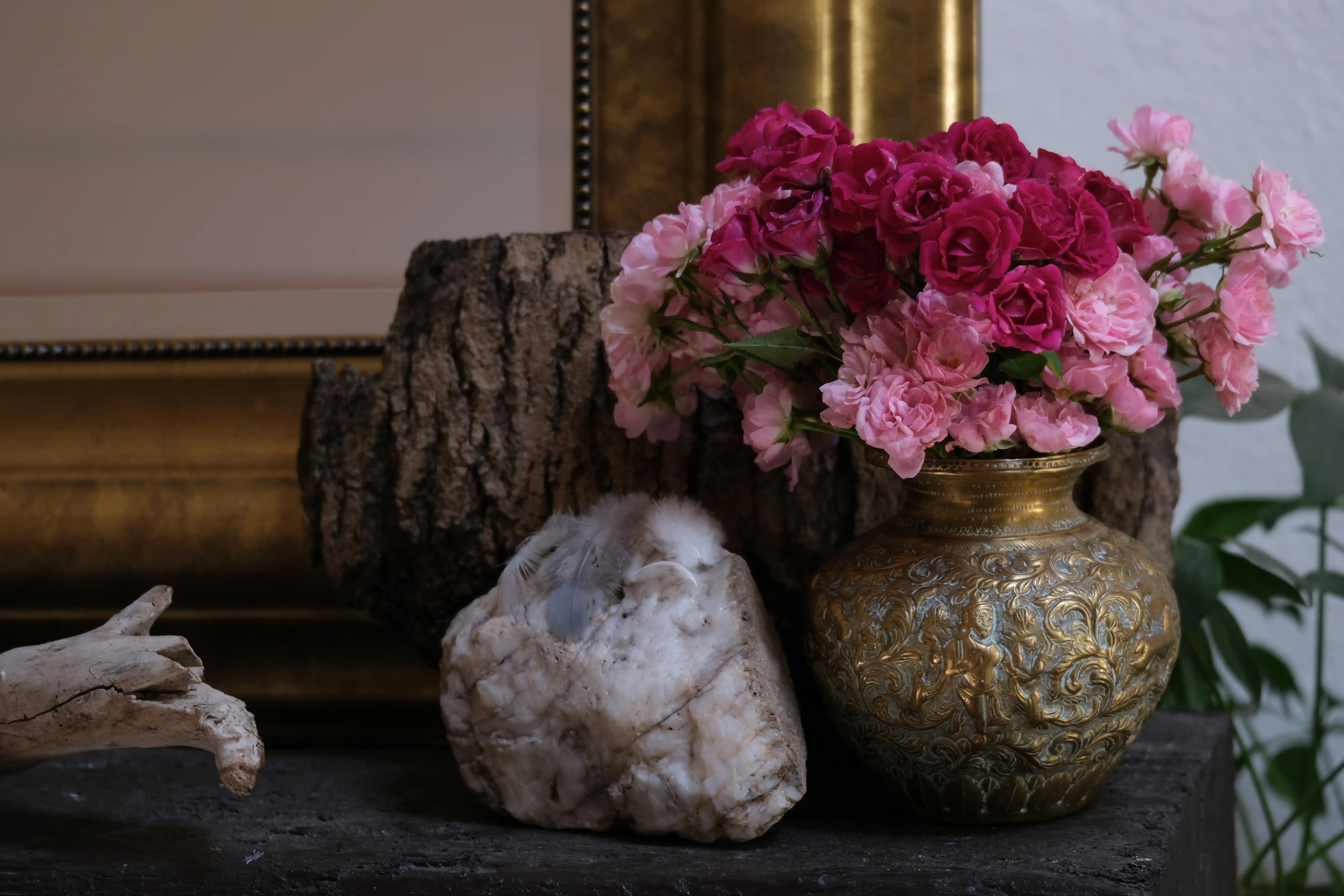 Freshly picked roses in an old copper vase on a fireplace