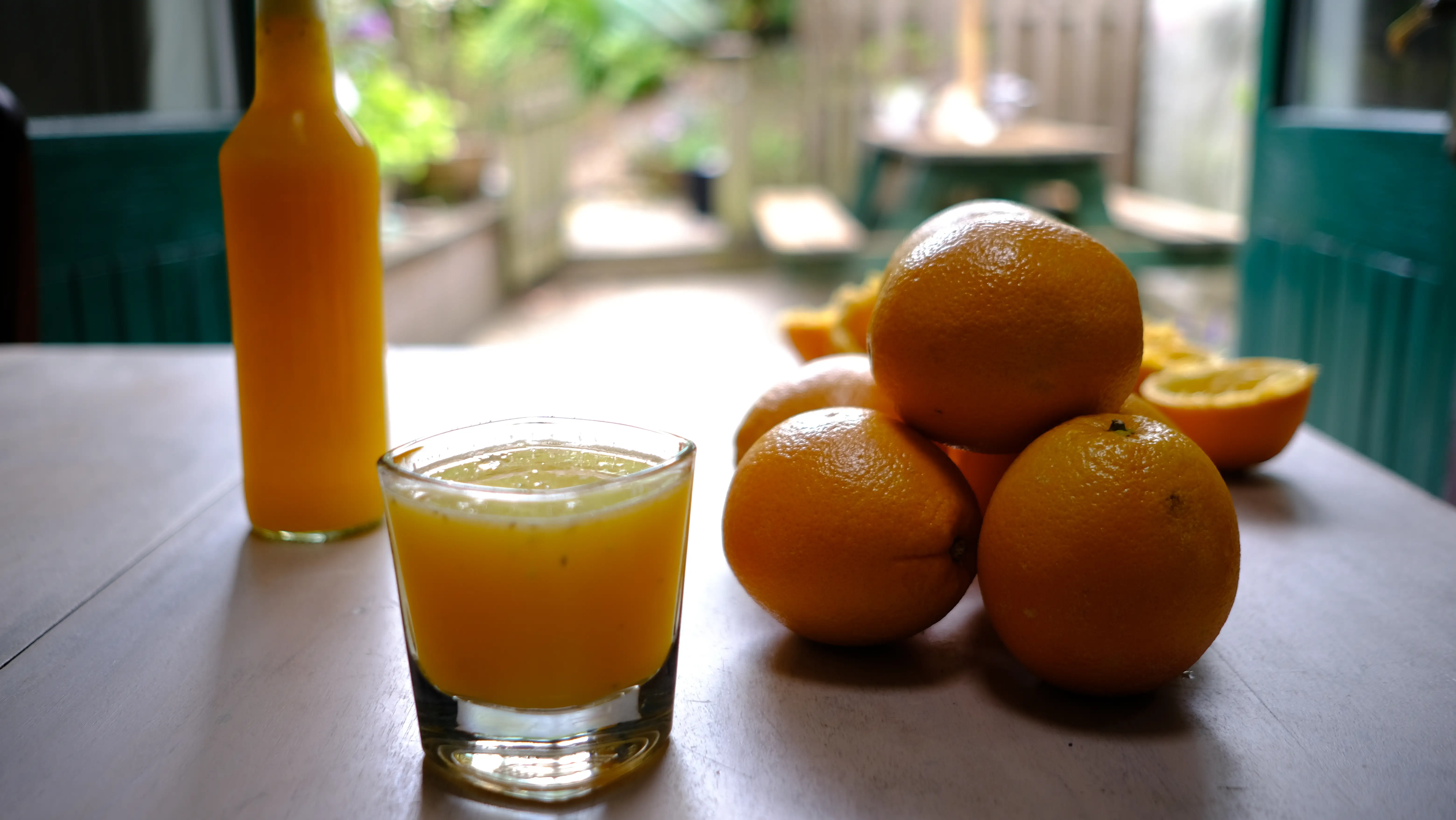 Freshly squeezed OJ with oranges and garden background 